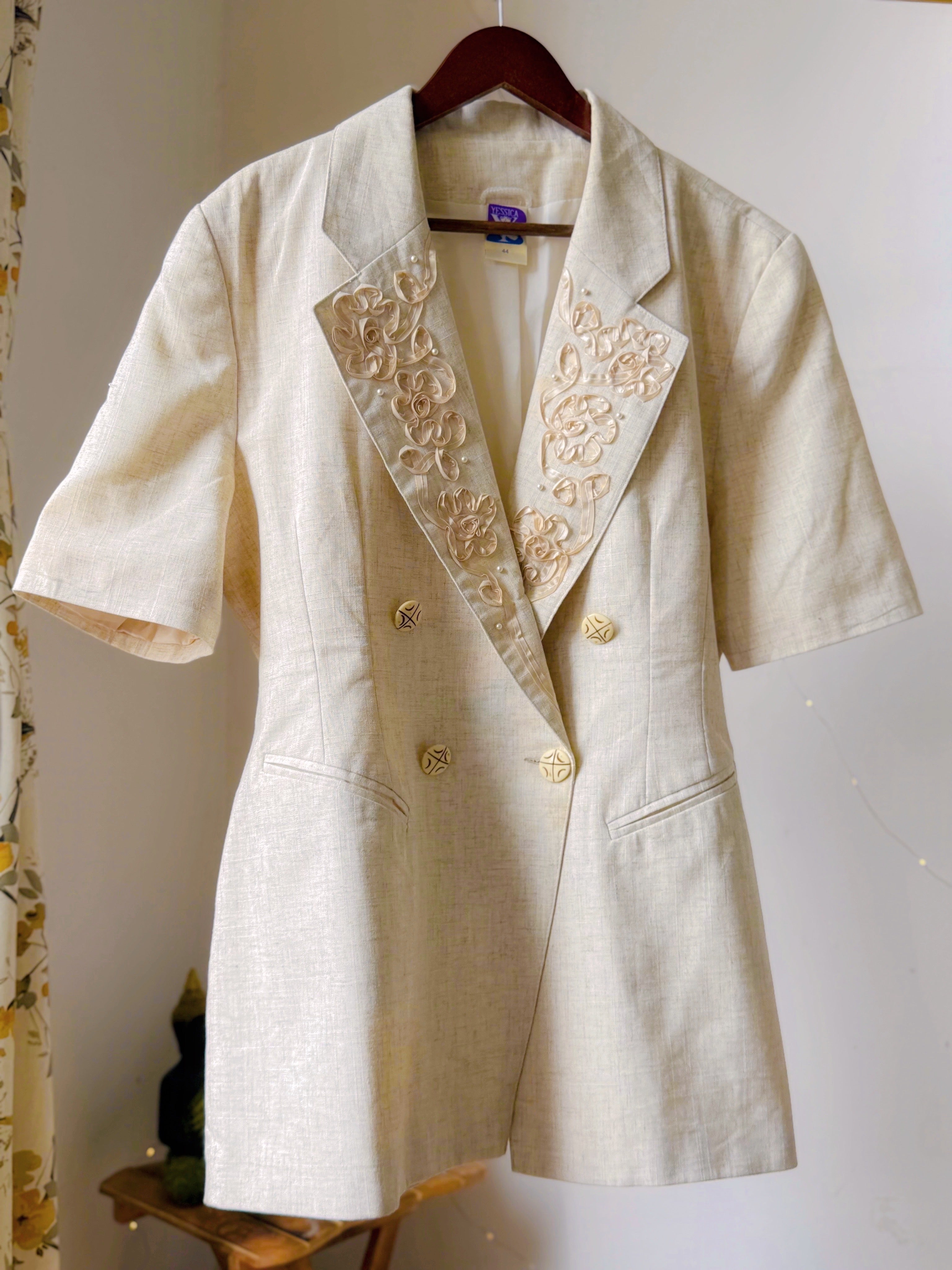 Ivory toned blazer with notched lapels, comes with embroidery work details on the collar.