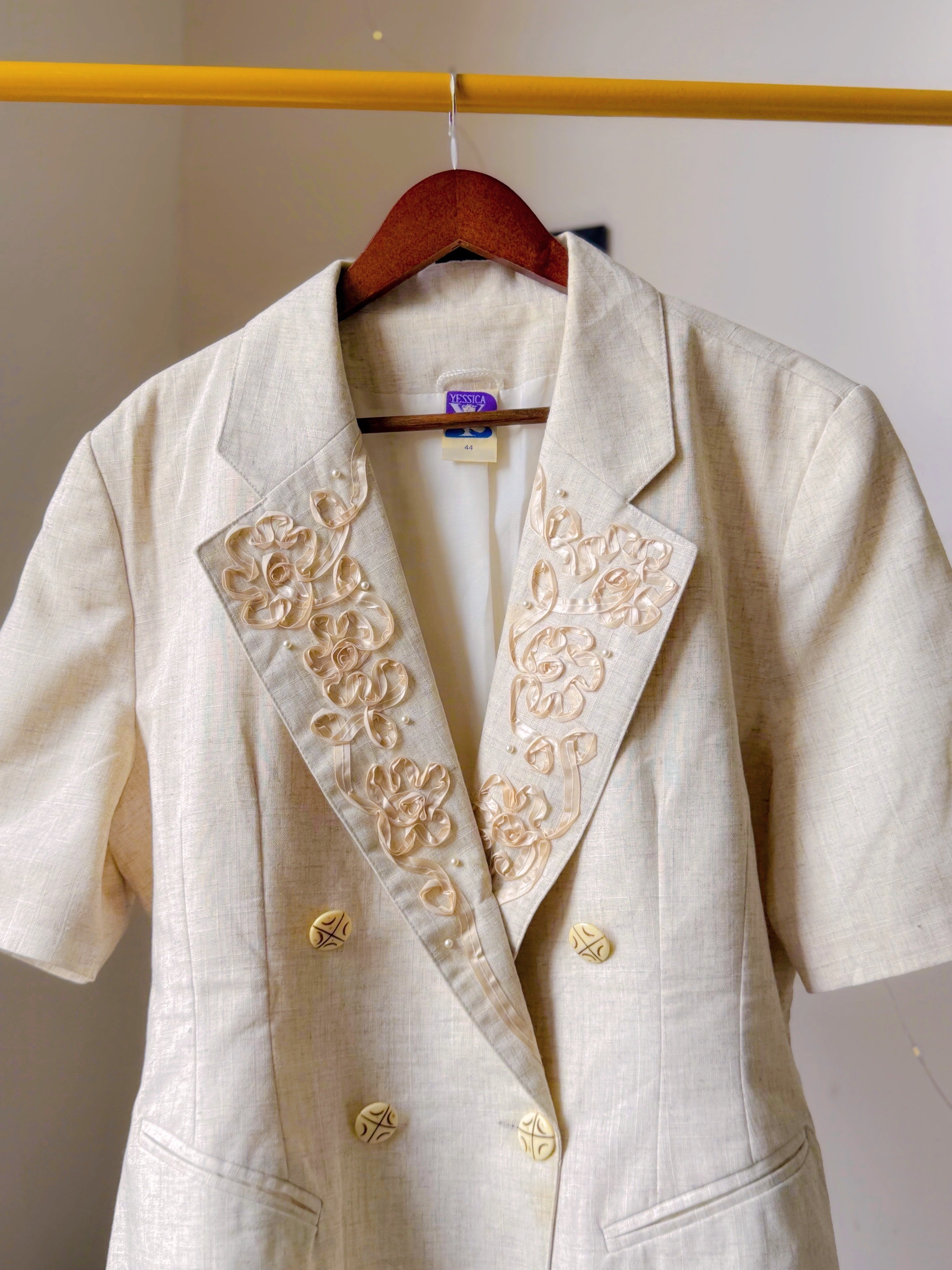 Ivory toned blazer with notched lapels, comes with embroidery work details on the collar.