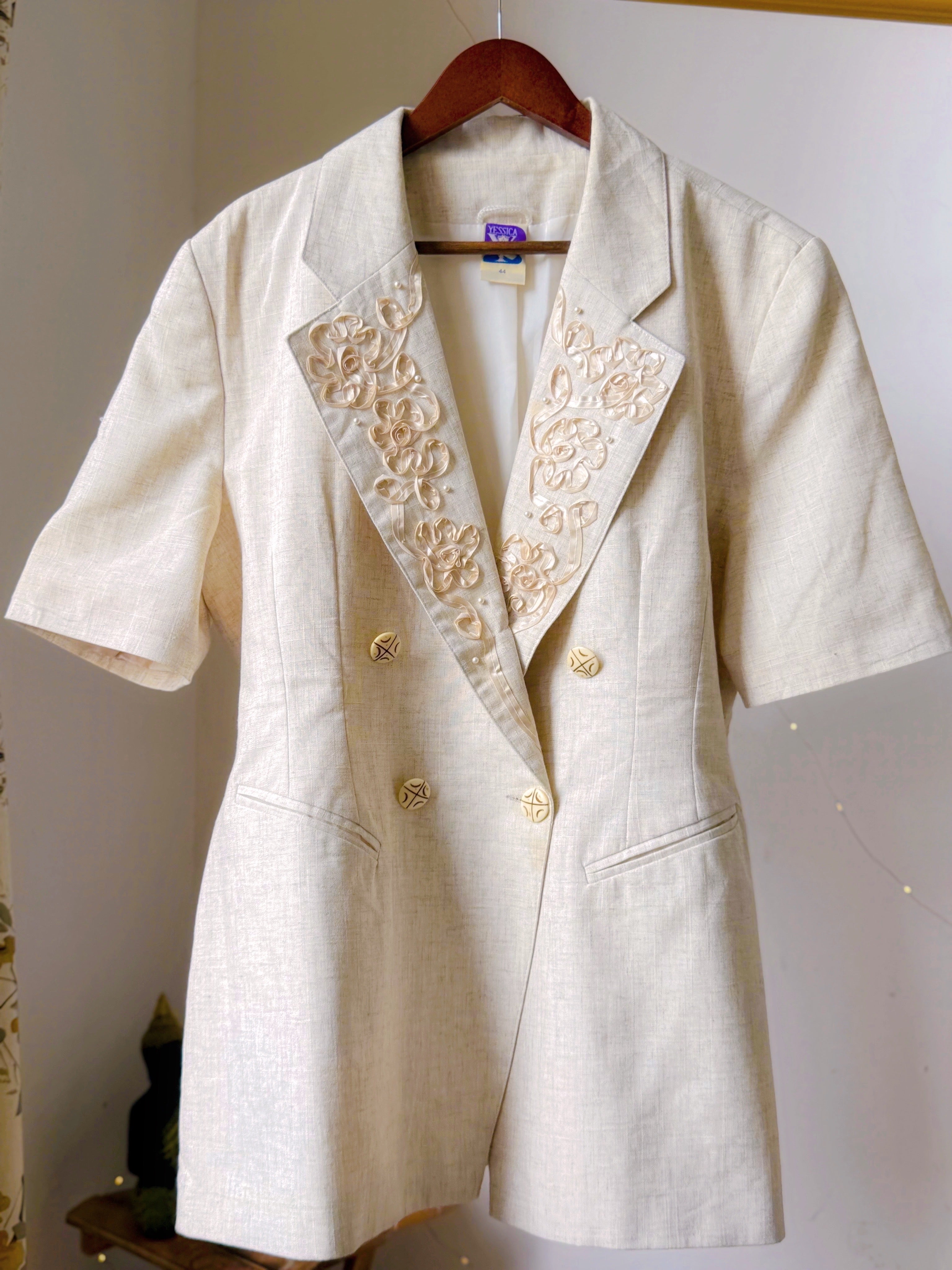 Ivory toned blazer with notched lapels, comes with embroidery work details on the collar.