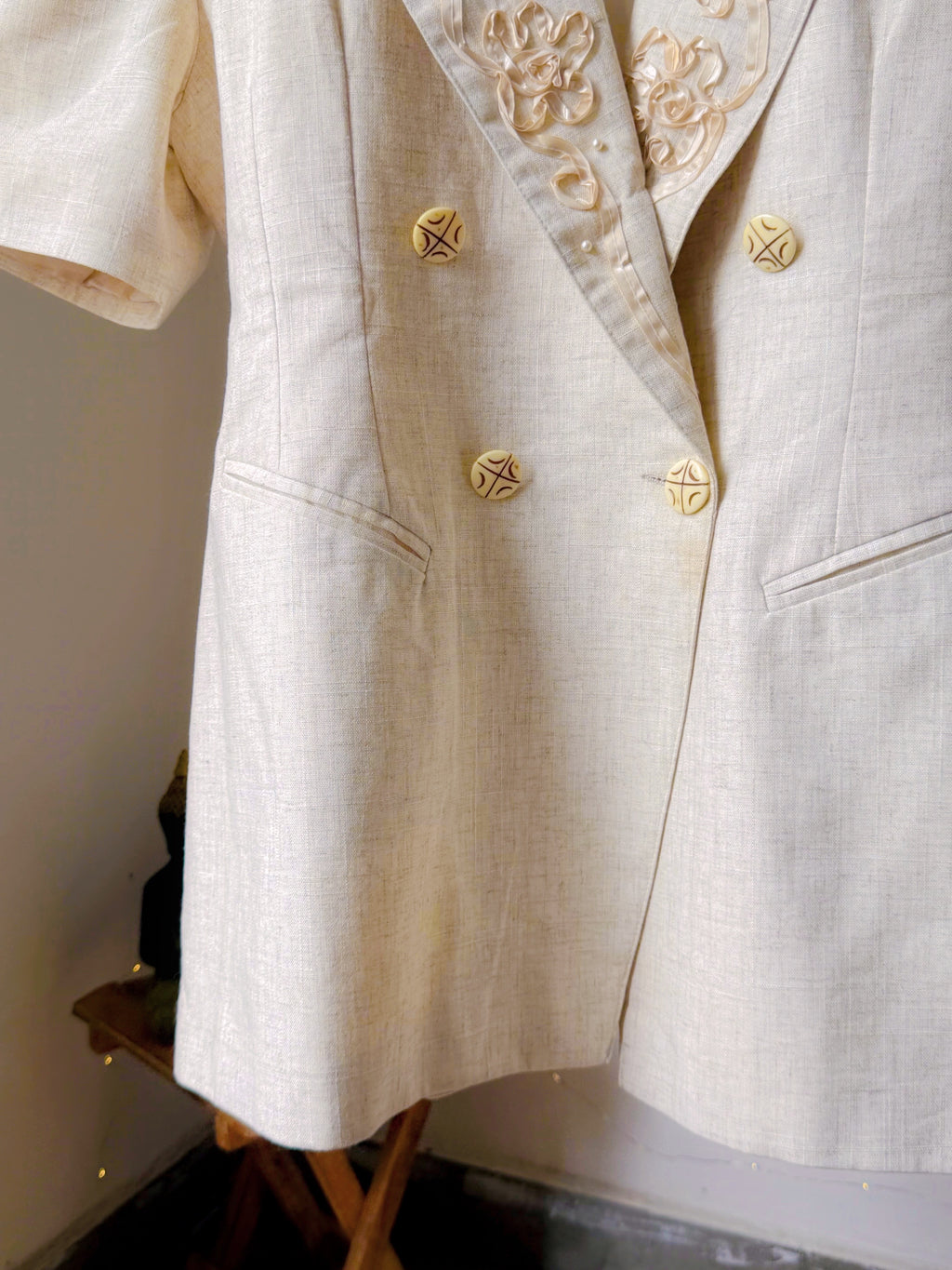 Ivory toned blazer with notched lapels, comes with embroidery work details on the collar.